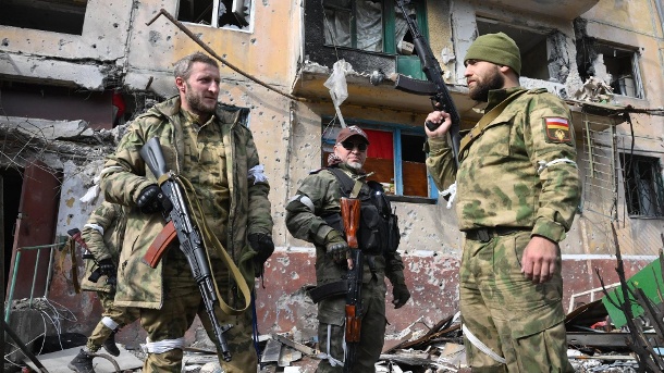 Prorussische Soldaten stehen vor zerstörten Häusern in Mariupol (Archivbild): Die Kämpfe im Osten des Landes dauern an. (Quelle: imago images/lya Pitalev)